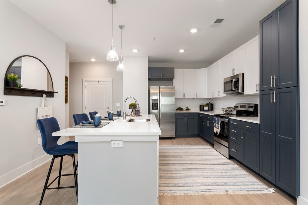 an open kitchen and dining area with a white island and black cabinets