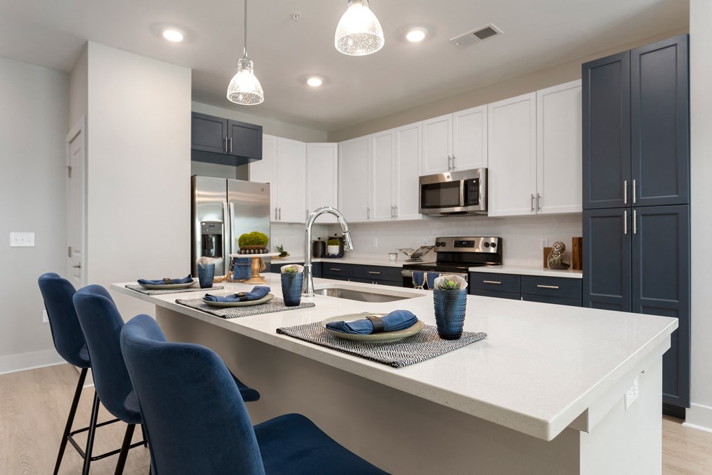 an open kitchen with a large island with blue chairs