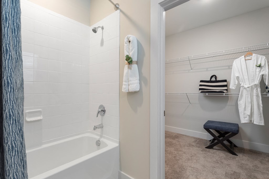a white bathroom with a tub and a shower and a towel rack
