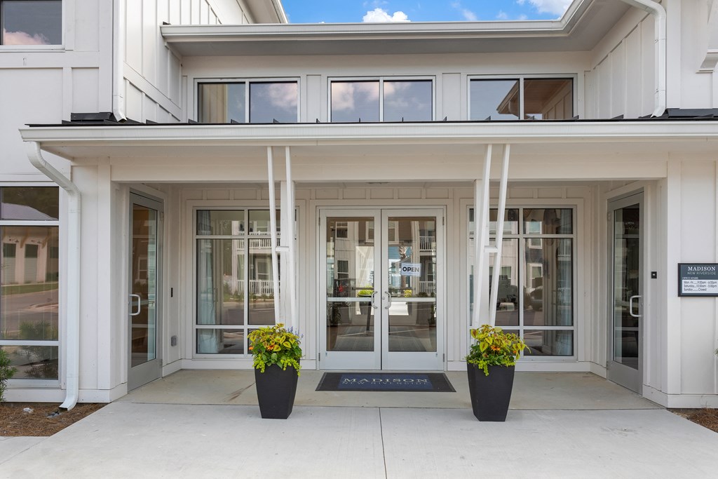 the front entrance of a white building with glass doors