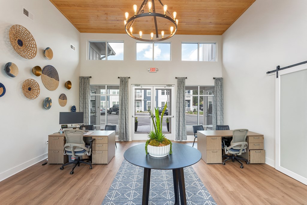 a living room with two desks and a table with a potted plant