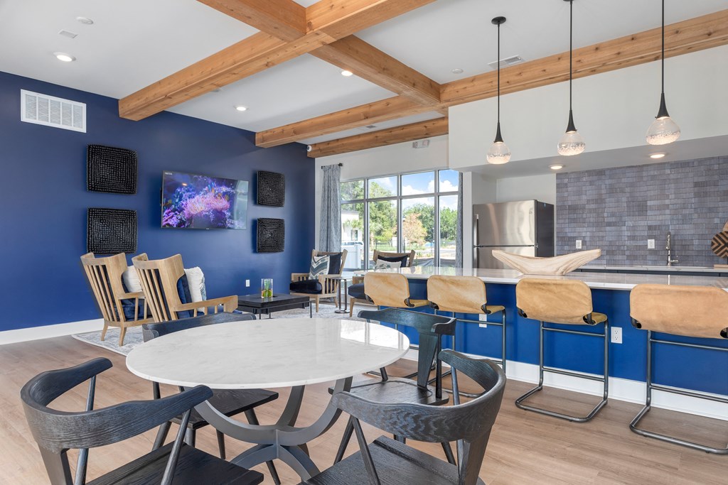 a dining room with tables and chairs and a kitchen with a blue wall and a