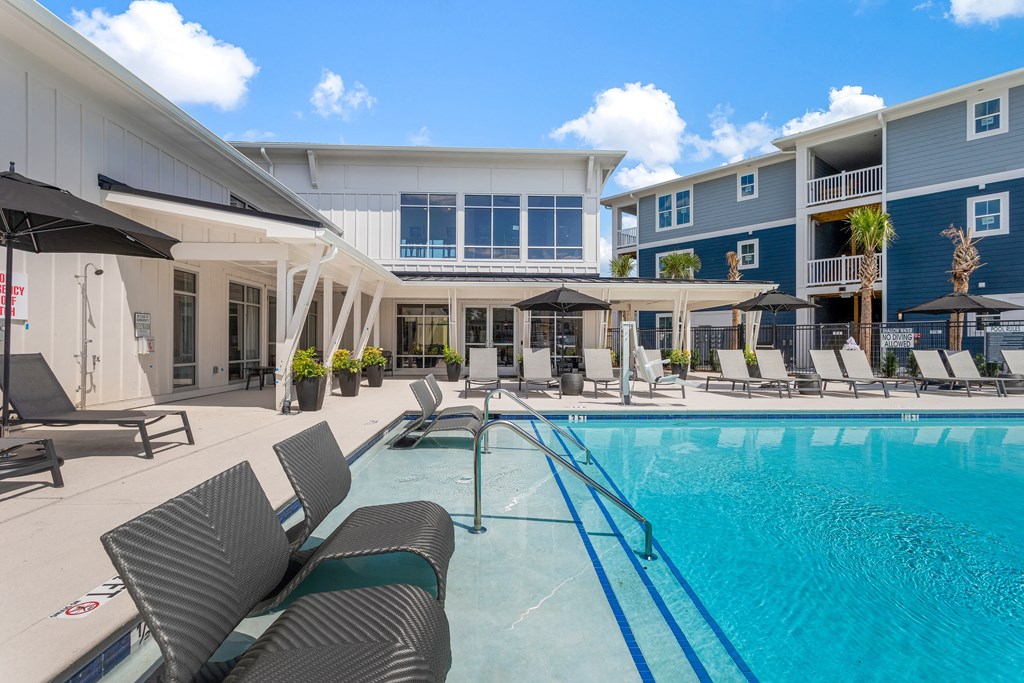 a swimming pool with chairs and umbrellas in front of a building