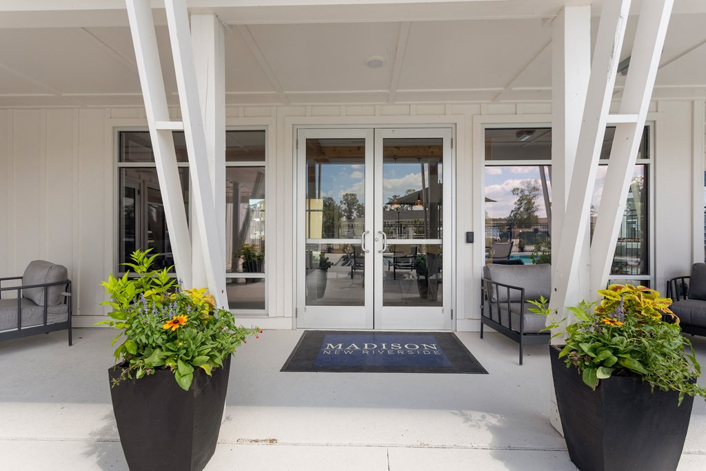 the front entrance of a building with glass doors and a rug