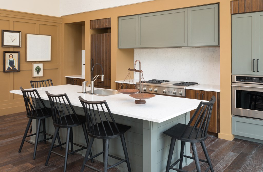 a kitchen with a white counter top and black chairs