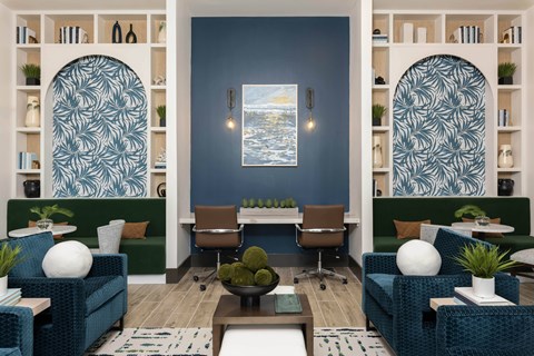 A living room with a blue couch and a painting on the wall.