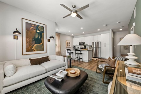 A modern living room with a white sofa and a painting on the wall.