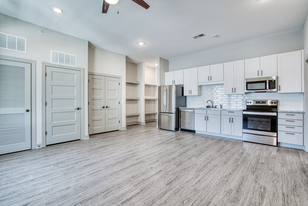 an empty kitchen with white cabinets and stainless steel appliances