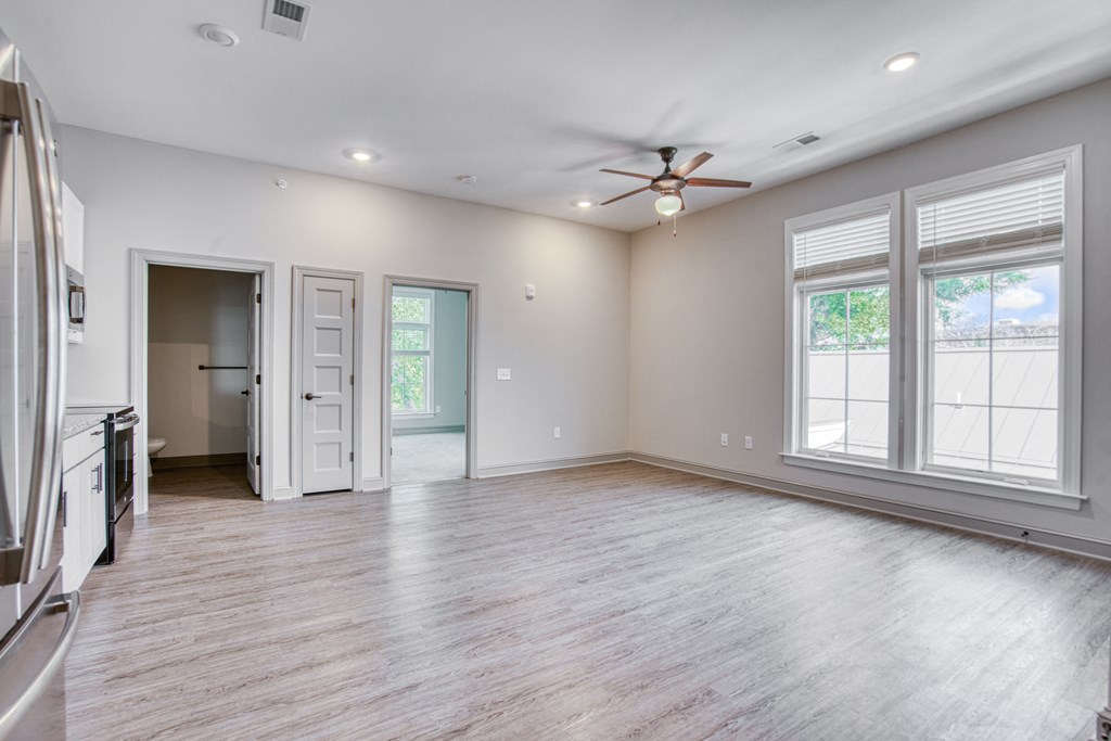 an empty living room with a ceiling fan and windows