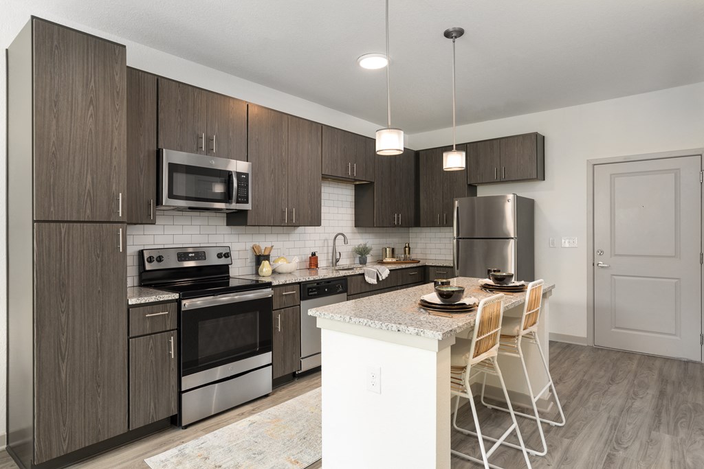 a kitchen with stainless steel appliances and a island with chairs