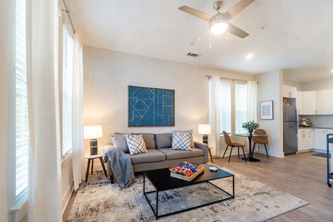 A living room with a grey couch and a blue painting on the wall.