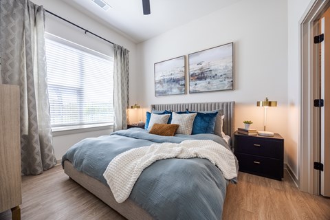 A bedroom with a large bed and a painting above it.
