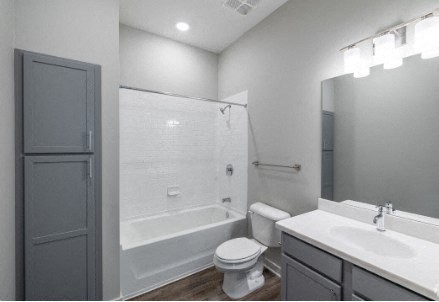 A white toilet sits in a bathroom next to a sink and a walk-in shower.