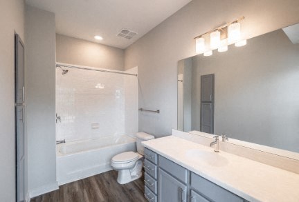 A bathroom with a toilet, sink, and mirror.
