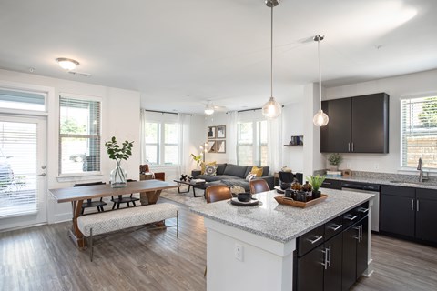 A modern kitchen with a wooden table and chairs, a bench, and a large island with a sink.