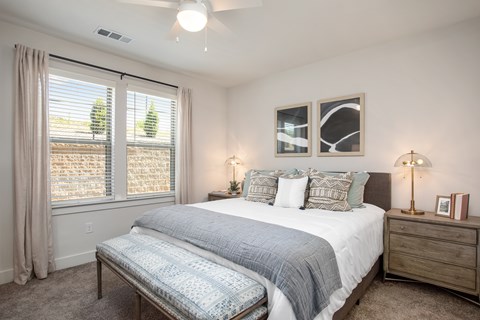 A bedroom with a large bed and a window with curtains.