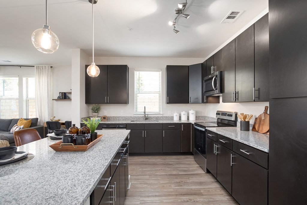 a large kitchen with black cabinets and granite counter tops