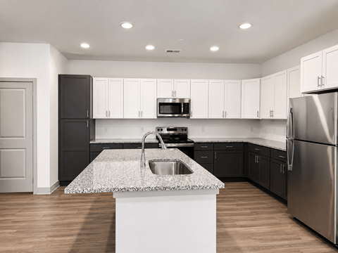 A modern kitchen with a granite countertop and stainless steel appliances.
