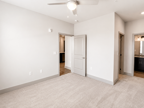 A spacious room with a ceiling fan and carpeted floor.
