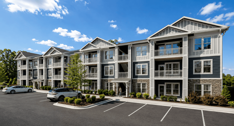 A large, modern apartment building with a parking lot in front.