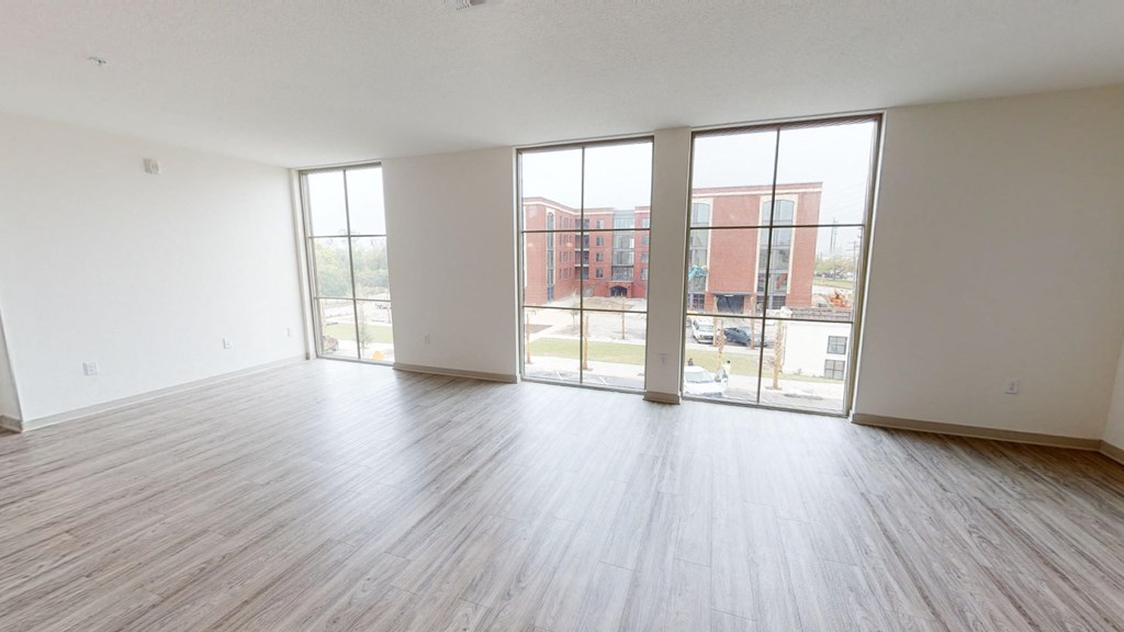an empty living room with wood flooring and sliding glass doors