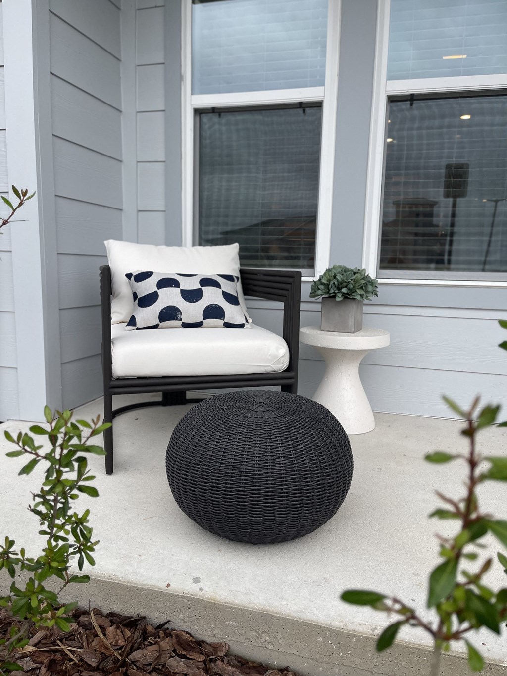 a black and white chair with a pillow on a porch