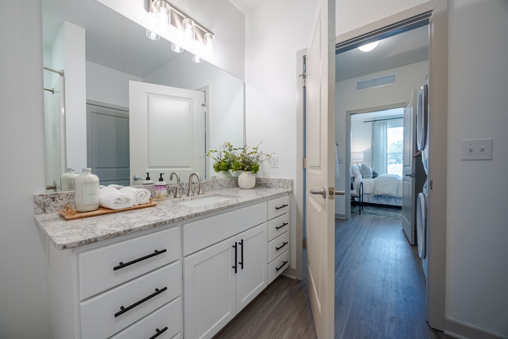 A bathroom with a marble countertop and white cabinets.