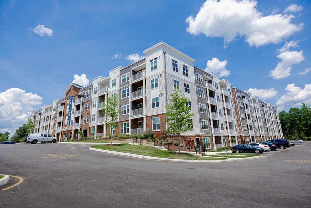 A large apartment complex with a parking lot in front.