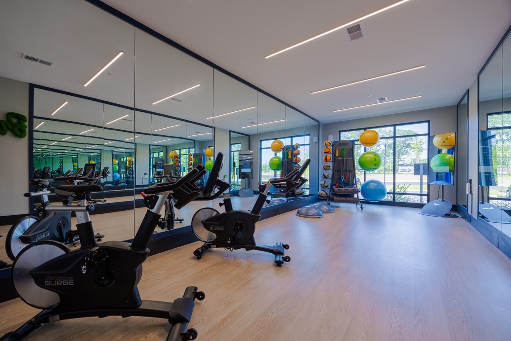 A gym with stationary bikes and a mirrored wall.