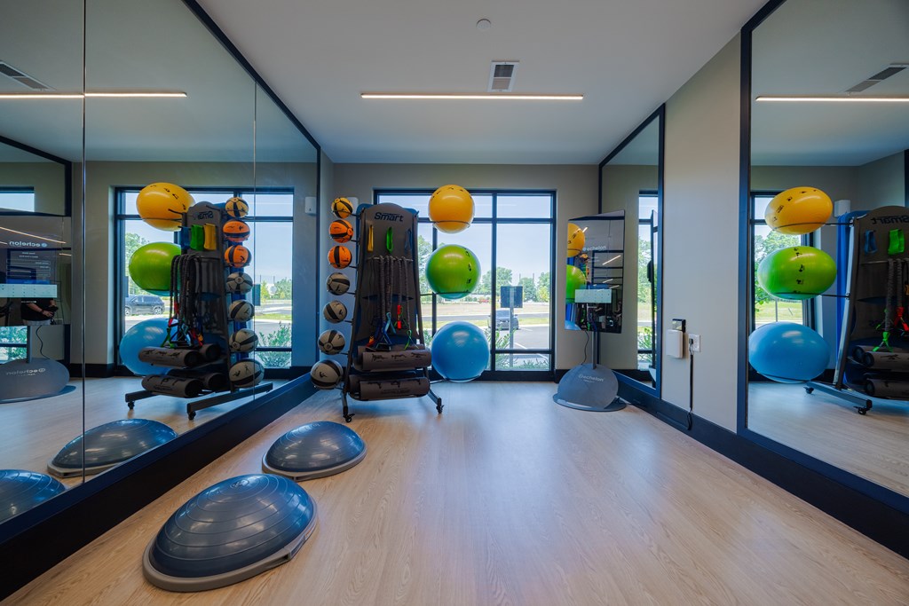 A gym with exercise equipment and mirrors on the wall.
