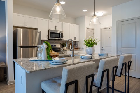 A kitchen with a counter and chairs.