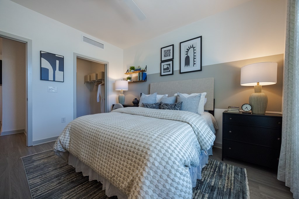 A bedroom with a large bed and a nightstand with a lamp.