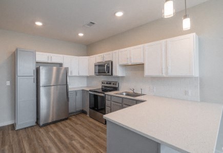 A kitchen with white cabinets and a stainless steel refrigerator.