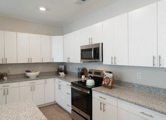 a kitchen with white cabinets and a stove and a microwave