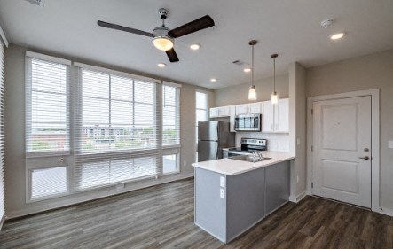 A kitchen with a fan and a fridge.