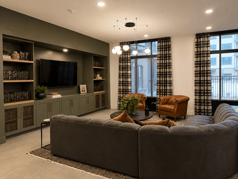 A living room with a grey sofa, a television, and a bookshelf.