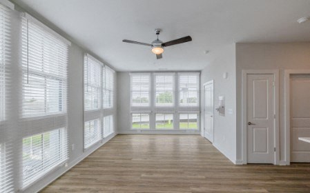 A room with a ceiling fan and sliding glass doors.