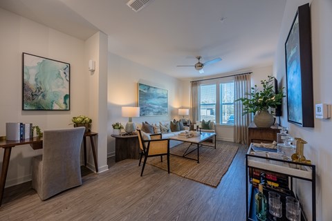 A living room with a couch, chairs, and a painting on the wall.