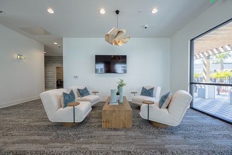 A modern living room with white furniture and a wooden coffee table.