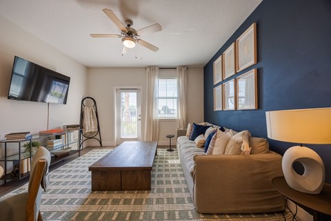 A living room with a brown couch and a ceiling fan.