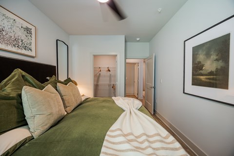 A bedroom with a bed covered in a green and white striped blanket.