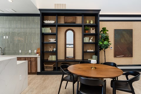 A modern kitchen with a round wooden table and black chairs.