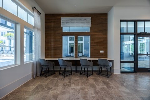 A room with a long table and chairs with a window on the left.