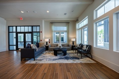 A spacious living room with a dark blue sofa and a wooden floor.