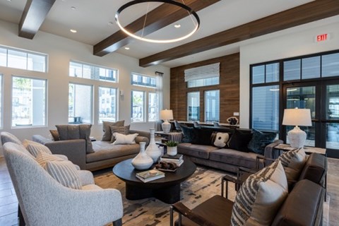 A living room with a grey couch, a white chair, and a brown armchair.