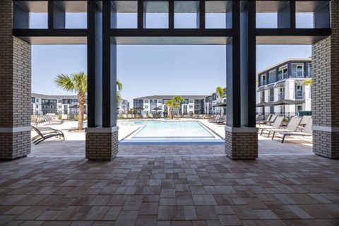 A pool area with a tiled floor and a view of a residential area through a framed opening.