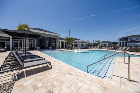 A pool with a slide and sun loungers.