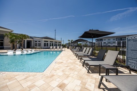 A pool with sun loungers and a warning sign.