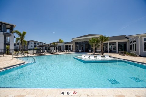 A large swimming pool with a depth marker reading 4'6" in front of a resort-style building.