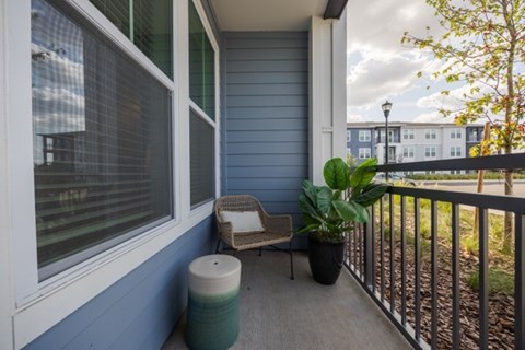 A balcony with a chair and a potted plant.
